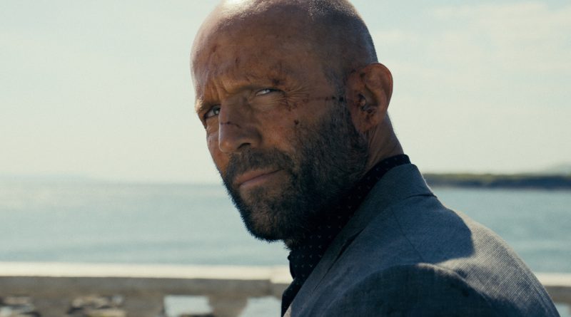 Jason Statham con heridas en el rostro mirando de reojo frente al mar en una escena de acción. Él protagonizará 'Jason Statham Stole My Bike'.