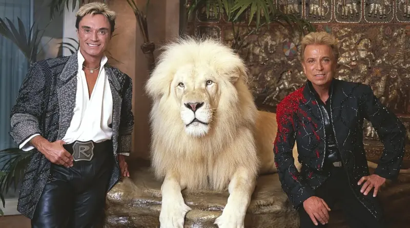 Los ilusionistas Siegfried y Roy posando junto a un león blanco.