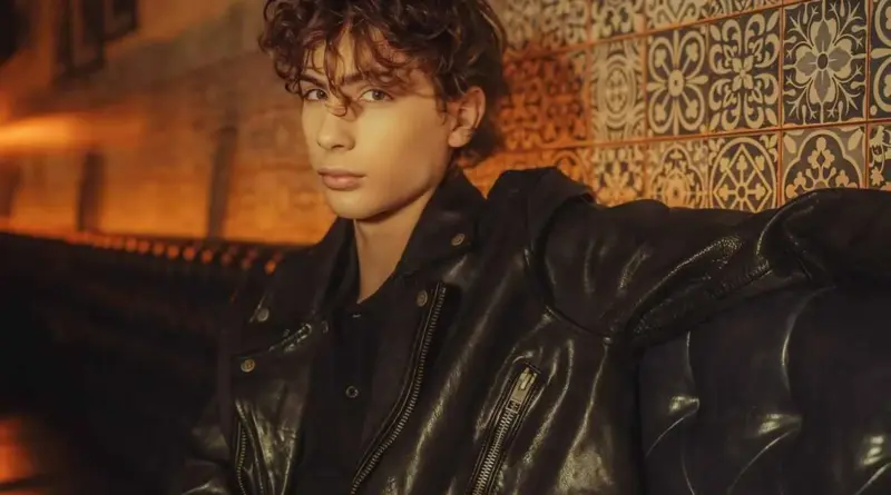 El actor Jacob Tremblay posando con una chaqueta de cuero negra frente a una pared de azulejos.