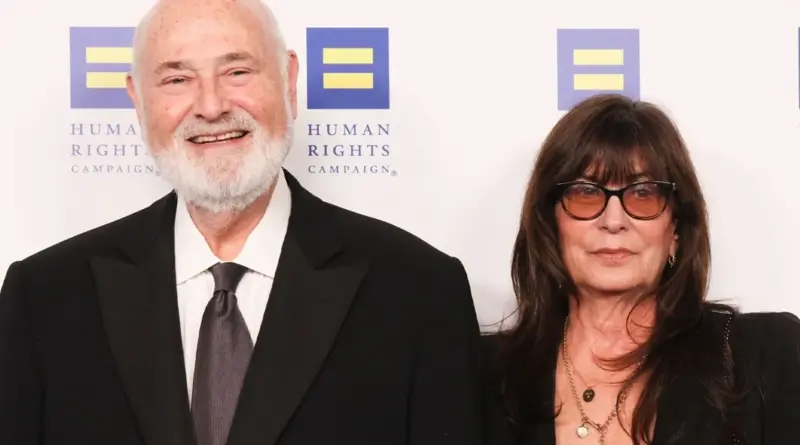 Fotografía de Rob Reiner y Michele Singer posando juntos en un evento de la 'Human Rights Campaign'. Rob, a la izquierda, es un hombre mayor con barba blanca y calvicie parcial, viste un esmoquin negro con corbata gris y sonríe ampliamente. A su derecha, Michele Singer luce una melena larga y oscura con flequillo y gafas de sol de cristales degradados, vistiendo una prenda negra y un collar dorado. El fondo es blanco con logotipos azules de la organización.