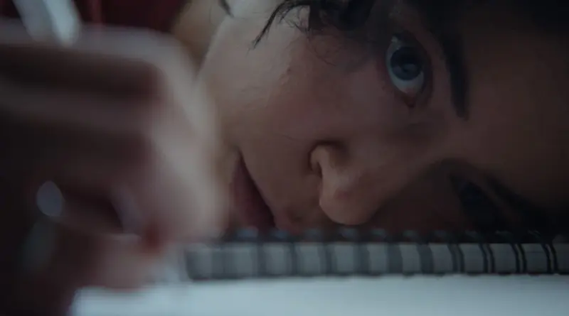 Primer plano extremo y lateral de la actriz Tatiana Maslany en la película 'The Keeper', con el rostro apoyado sobre un cuaderno de espiral y la mirada fija y tensa hacia la cámara.