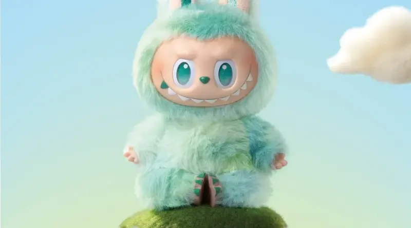 Figura coleccionable de Labubu de Pop Mart, un monstruo elfo de color verde azulado con pelaje suave, grandes ojos verdes y sonrisa de dientes afilados, sentado sobre una pequeña colina de hierba.