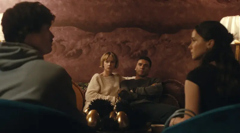 Fotograma de la temporada 2 de 'Beef' ('Bronca'). Plano medio en un salón con papel pintado rojo. Carey Mulligan (preocupada) y Oscar Isaac (brazos cruzados y serio) están sentados en un sofá mirando hacia el frente, mientras las siluetas de Charles Melton y Cailee Spaeny se ven de espaldas en primer plano enfrentándolos.