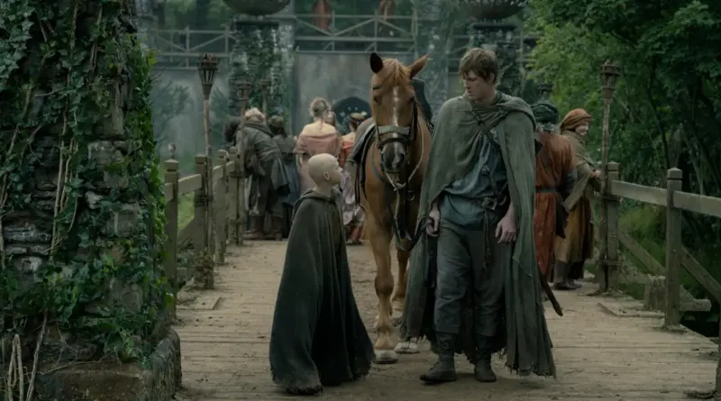 Crítica de 'El caballero de los Siete Reinos': La serie de 'Juego de Tronos' que te atrapará con la picaresca de unos personajes en el Poniente más realista. 1 Fotograma de la serie 'El Caballero de los Siete Reinos'. Un joven caballero alto (Peter Claffey como Dunk) camina junto a su caballo marrón por un puente de madera en un entorno medieval, acompañado por un niño con la cabeza rapada (Dexter Sol Ansell como Egg). Al fondo, se ve un castillo de piedra y varias personas vestidas con ropas de época caminando. El caballero lleva una capa verde desgastada y una espada al cinto.