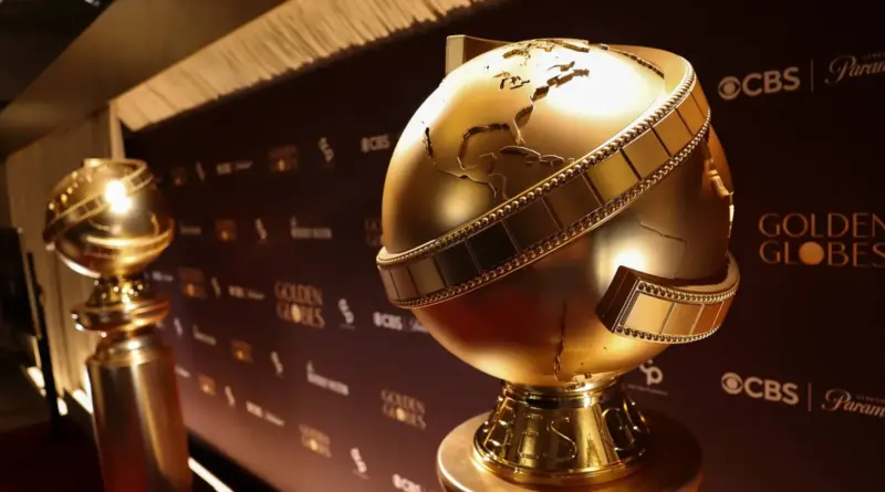 ¿Dónde ver los Globos de Oro 2026 en España? Guía de supervivencia para esos cinéfilos valientes que trasnocharán. 1 Primer plano detallado de la estatuilla dorada de los Globos de Oro sobre un pedestal, con un fondo oscuro desenfocado que muestra los logotipos de CBS y Paramount.