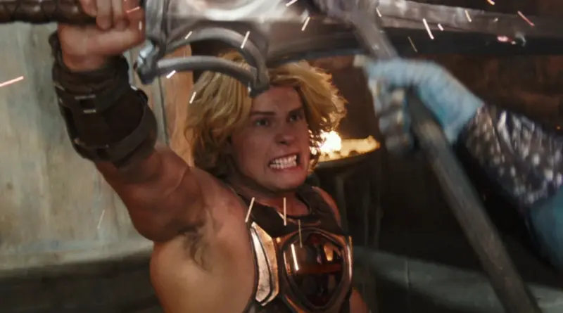 ¡Por el poder de Grayskull! El primer tráiler de 'Masters del universo' muestra a Nicolas Galitzine como He-Man. 1 Fotograma de 'Masters del Universo'. Primer plano de He-Man gritando con fuerza mientras sostiene la Espada del Poder sobre su cabeza con ambas manos. Lleva la icónica armadura de pecho plateada con la cruz roja y brazaletes de cuero, rodeado de chispas mágicas.