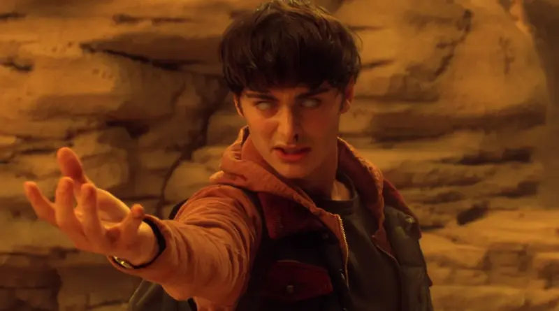 Primer plano de Will Byers (Noah Schnapp) en 'Stranger Things' con los ojos completamente blancos, una expresión de ira contenida y sangre fluyendo de su fosa nasal izquierda, extendiendo su mano derecha hacia adelante en un entorno desértico de tonos anaranjados.