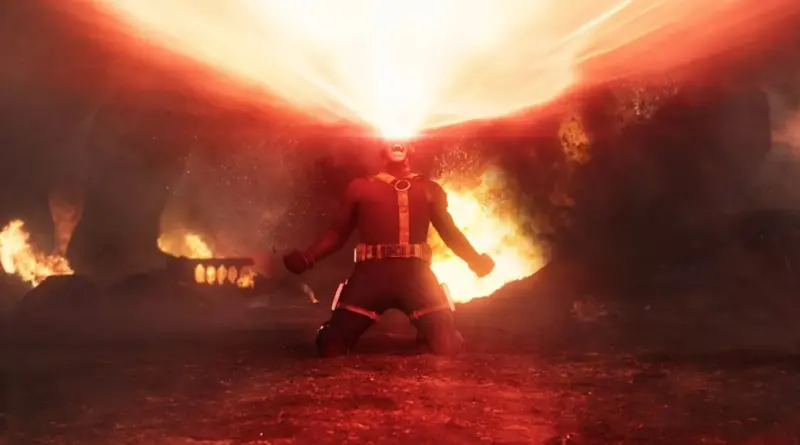Cíclope (Scott Summers) arrodillado en un campo de batalla devastado, lanzando un potente y masivo rayo óptico de color rojo brillante desde sus ojos hacia el cielo, rodeado de fuego y escombros en el teaser tráiler de 'Vengadores: Doomsday'.