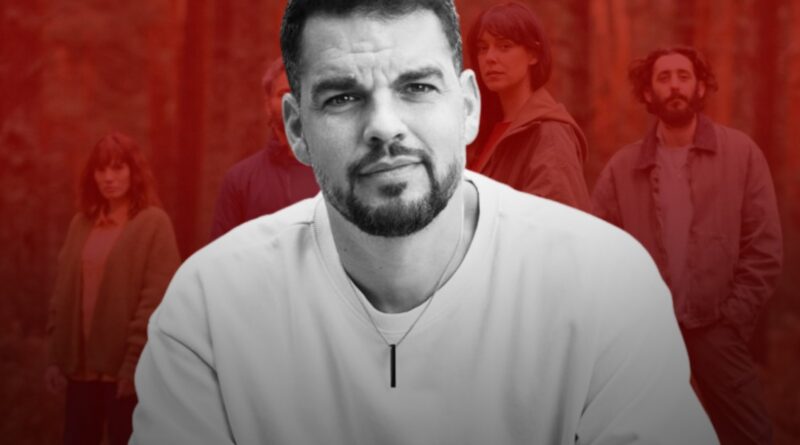 Composición Gráfica Editorial. En Primer Plano Y En El Centro, Un Retrato En Blanco Y Negro Del Director David Victori Mirando A Cámara Con Expresión Seria Y Barba Recortada. Viste Una Sudadera Clara Y Un Colgante Minimalista. El Fondo Está Teñido De Rojo Sangre Y Muestra A Los Cuatro Protagonistas De La Película De Pie Entre Árboles En Un Bosque.