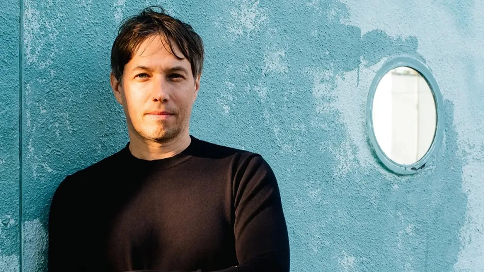 Primer plano del director de cine Sean Baker frente a una pared azul.