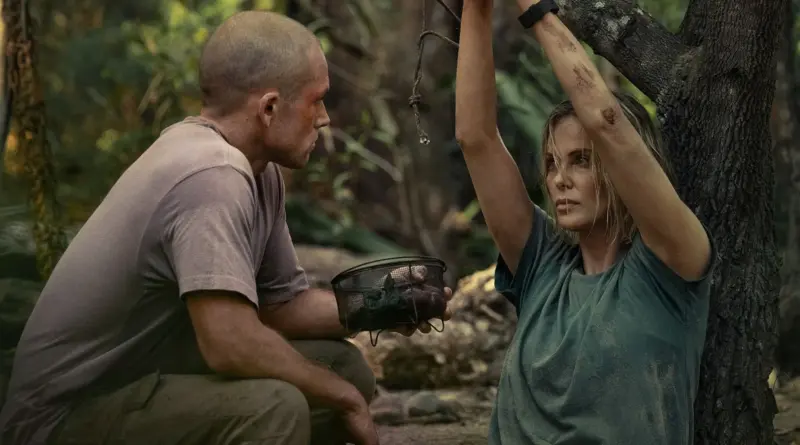 Fotograma De 'Depredador Dominante'. Taron Egerton Amenazando Con Un Cuchillo A Charlize Theron, Quien Tiene Las Manos Encadenadas.