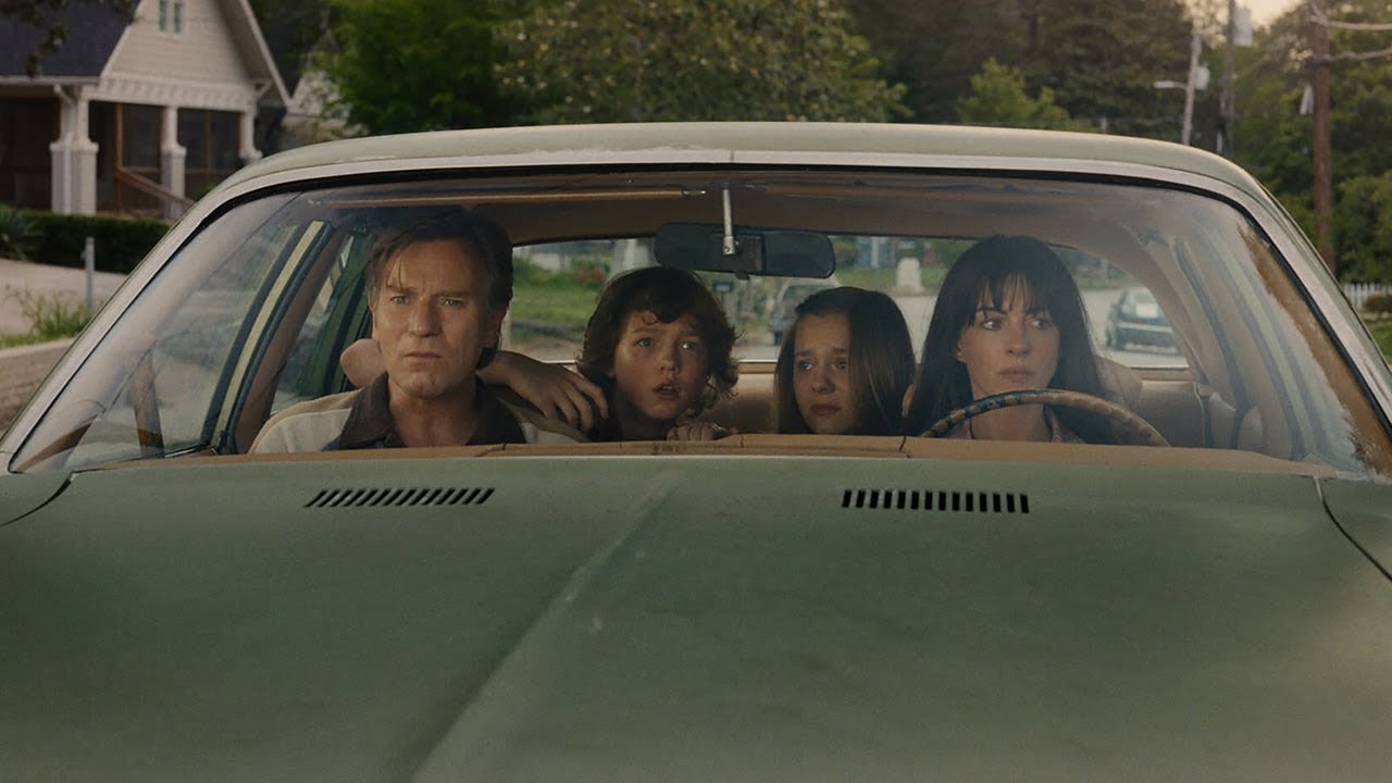 Fotograma de la película 'El final de Oak Street'. Anne Hathaway, Ewan McGregor y dos menores con caras de incredulidad dentro de un coche verde.