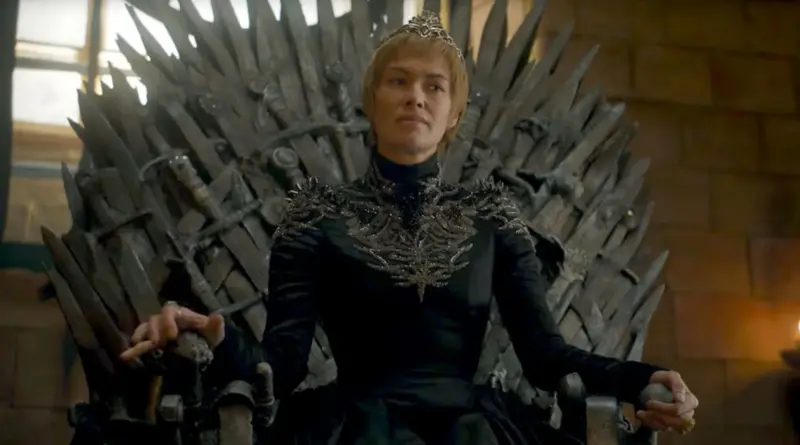 Fotograma De 'Juego De Tronos'. Cersei Lannister Sentada Regiamente En El Trono De Hierro Con Expresión Severa, Vistiendo Un Vestido Negro Con Detalles Metálicos Y Una Corona.