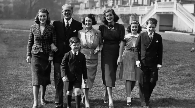 Fotografía en blanco y negro de varios miembros de la familia Kennedy caminando de frente por el césped.