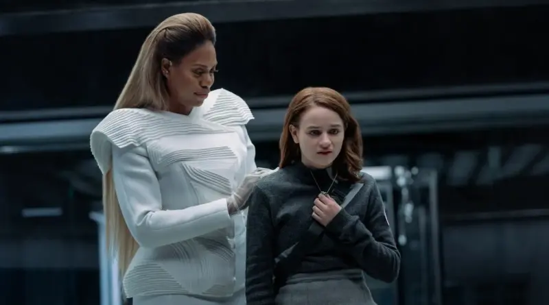 Laverne Cox Con Traje Blanco Futurista Poniendo La Mano En El Hombro De Joey King En La Película Los Feos.
