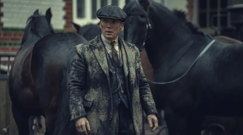 Cillian Murphy Como Thomas Shelby En Peaky Blinders: El Hombre Inmortal, Luciendo Un Abrigo Sucio De Barro Y Una Gorra Plana, Rodeado De Caballos Negros En Un Ambiente Industrial.