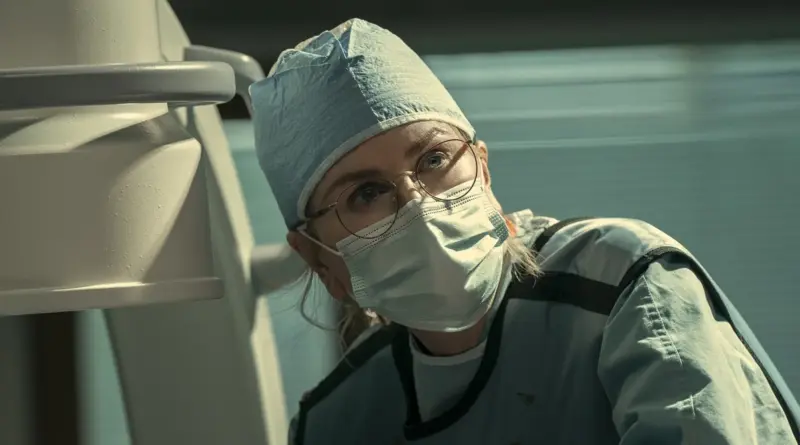 Fotograma De 'Scarpetta'. Nicole Kidman Caracterizada Como La Forense Kay Scarpetta Con Traje Quirúrgico, Mascarilla Y Gafas.