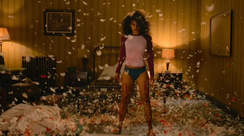 Fotograma De La Película 'Te Van A Matar'. Mujer Ensangrentada Sosteniendo Un Machete En Un Dormitorio Lleno De Plumas Volando.