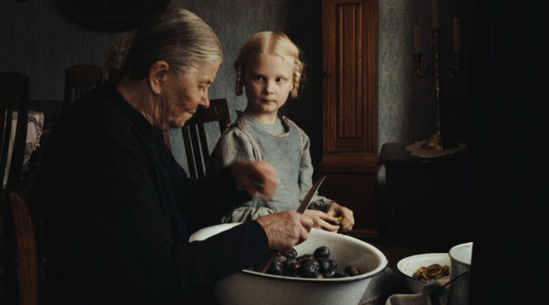 Escena de la película El sonido de la caída donde una mujer anciana y una niña preparan fruta en una cocina rústica.
