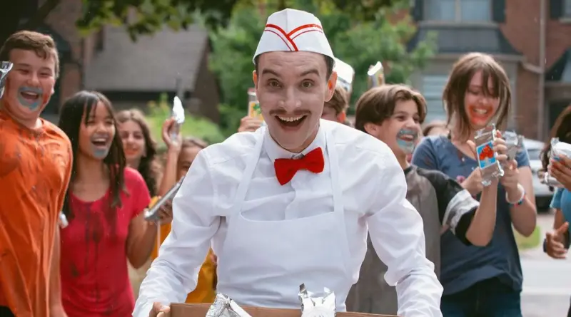El personaje del heladero sonriendo rodeado de niños en una escena de Ice Cream Man (2026).