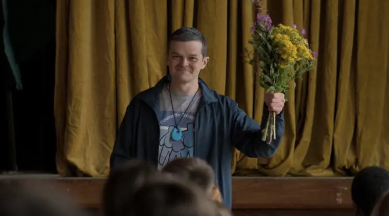 El Protagonista De Incontrolable Sosteniendo Un Ramo De Flores Silvestres Sobre Un Escenario Con Cortinas Doradas.