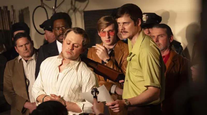 Escena de Prime Crime: A True Story donde Bill Skarsgård apunta con una escopeta a un rehén frente a cámaras y micrófonos.