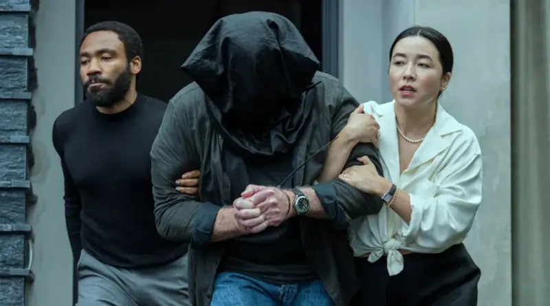 Escena de Mr. & Mrs. Smith donde John y Jane escoltan a un hombre con la cabeza cubierta.