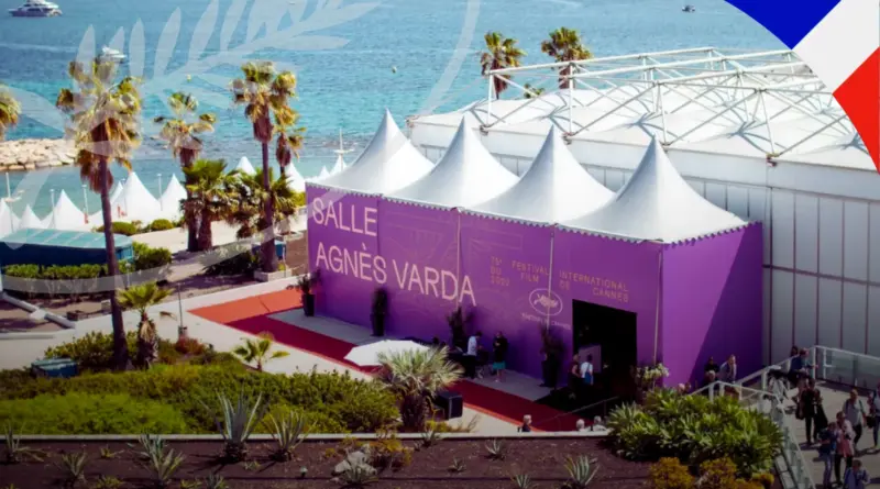 Exterior De La Salle Agnès Varda En El Festival De Cannes Con Su Distintiva Fachada Color Púrpura Y Carpas Blancas Frente Al Mar.