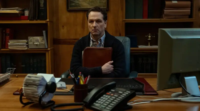 Matthew Rhys Sentado Seriamente En Un Escritorio De Oficina Con Estética De Los Años 90 En Una Escena De La Serie La Maldición De Widow'S Bay De Apple Tv.