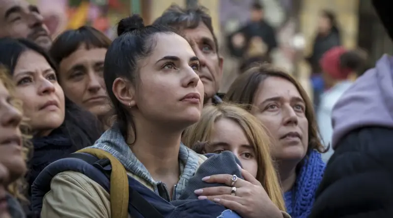 Primer plano de la protagonista de Yo siempre a veces mirando hacia arriba con esperanza entre una multitud de personas.