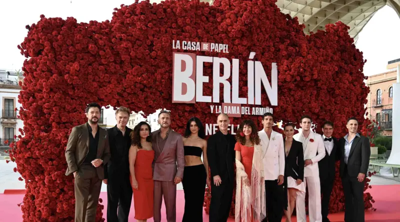 El equipo de la serie Berlín posa en la premiere celebrada en Sevilla, frente a un gran muro de claveles rojos con el título "Berlín y la dama del armiño".