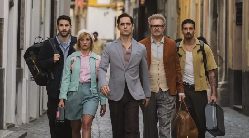 Fotograma de Berlín y la dama del armiño. Los cinco miembros principales de la banda de Berlín caminando juntos por un estrecho callejón empedrado, cargando maletas y equipo.