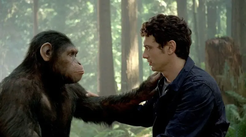 El chimpancé César pone su mano sobre el hombro de un joven humano en medio de un bosque.