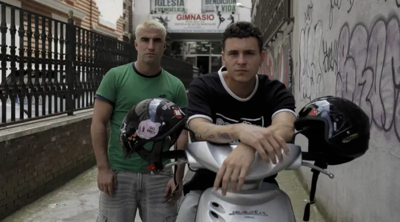 Marco Cáceres y Arón Piper posando con una scooter en un callejón urbano para Hugo 24.