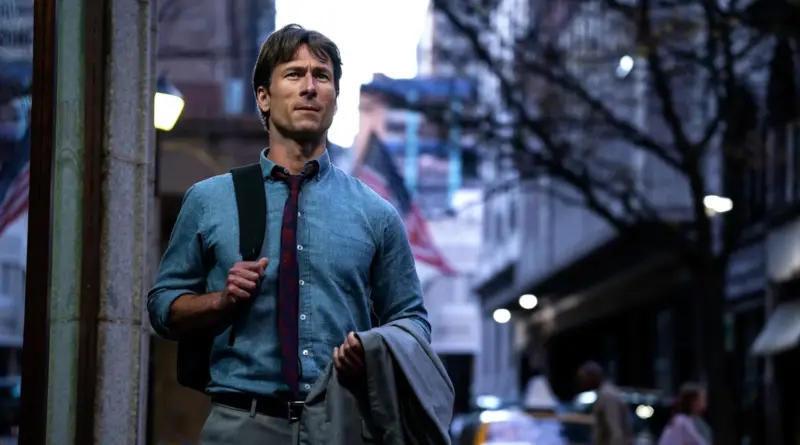 Glen Powell caminando por una calle de la ciudad en una escena de Jugada Maestra.