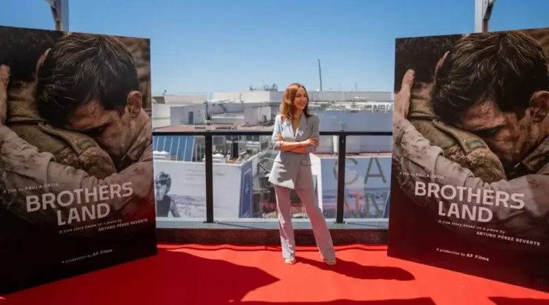 La directora Paula Ortiz posa en una terraza del Festival de Cannes entre dos carteles de su película "Brothers Land", la adaptación de Arturo Pérez-Reverte.