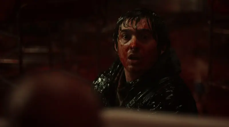 Primer plano de un hombre con el rostro cubierto de sangre y expresión de shock en Resident Evil.