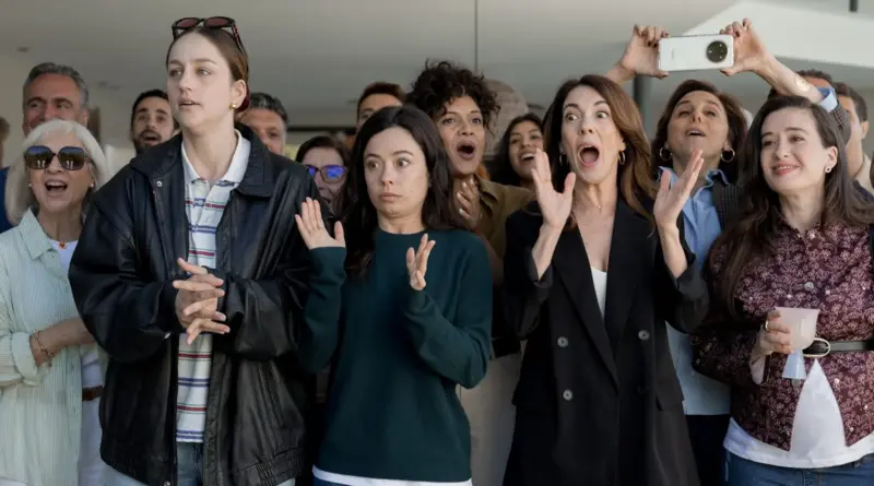 Escena de la serie Se tiene que morir mucha gente con un grupo numeroso de personas expresando sorpresa, asombro y euforia en un espacio exterior iluminado.