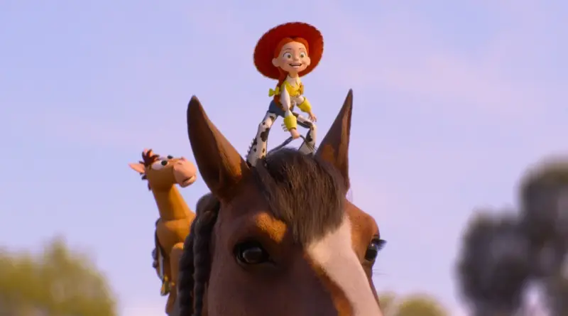 Fotograma de Toy Story 5 que muestra a la vaquera Jessie sonriente montada sobre la cabeza del caballo Perdigón en un plano contrapicado con el cielo de fondo.