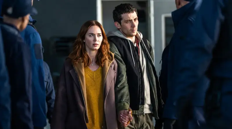 Emily Blunt y Josh O'Connor caminando tomados de la mano entre una multitud de espaldas en la película El día de la revelación (Disclosure Day).