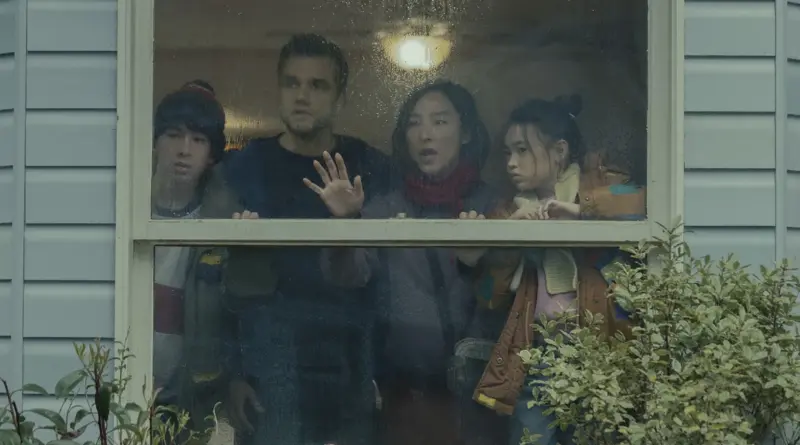 Escena de La última casa donde una familia de cuatro miembros mira con asombro y preocupación a través de una ventana empañada por la lluvia.