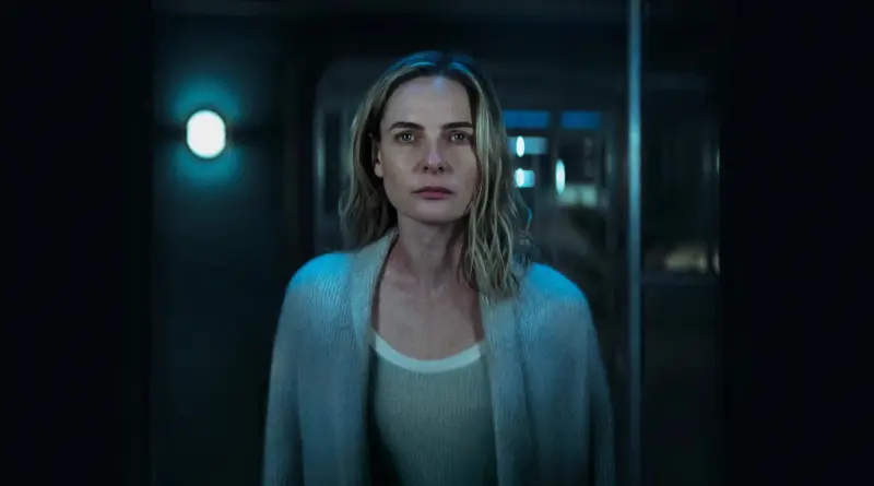 Primer plano de la protagonista de Silo en un pasillo oscuro con iluminación azulada.