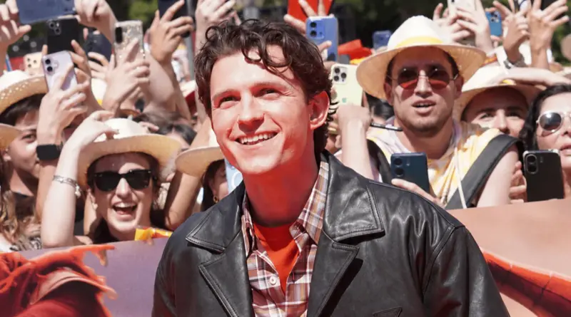 Primer plano de Tom Holland sonriendo a la prensa y al público en una alfombra roja en Madrid.