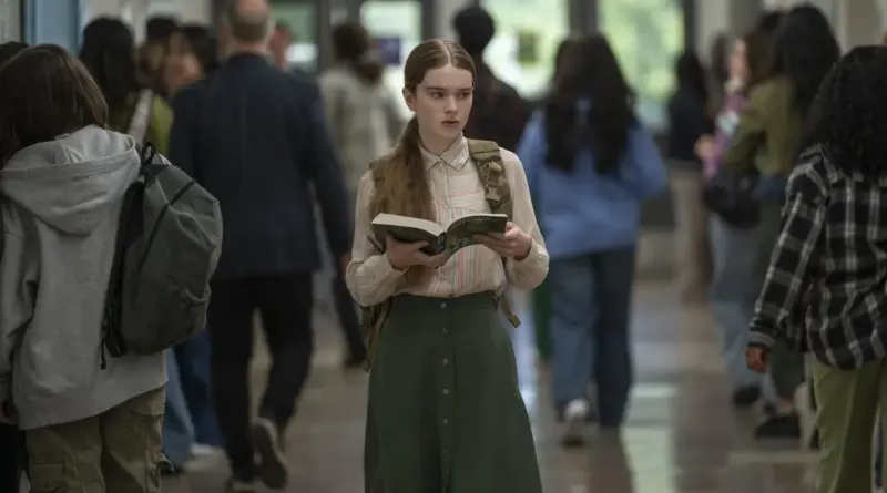 Carrie camina solitaria, asustada y abrazando un libro por el pasillo lleno de estudiantes en la serie de Prime Video.