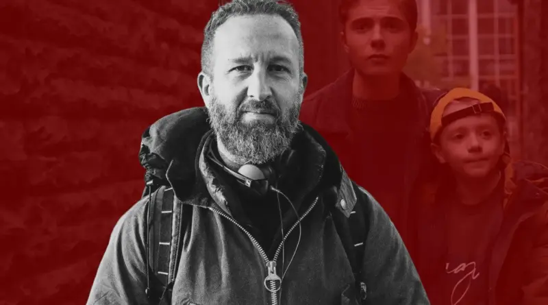 A 500 millas de casa. Retrato del director Morgan Matthews en blanco y negro con dos niños en un fondo rojizo.