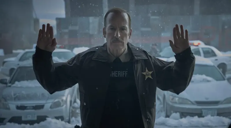 El protagonista de la película Normal, Bob Odenkirk, rindiéndose con las manos en alto bajo la nieve.