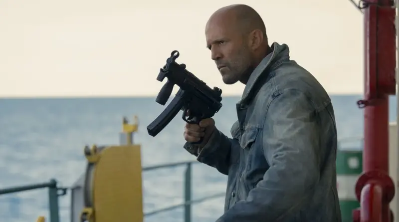 Jason Statham sosteniendo un subfusil en la cubierta de un barco a plena luz del día en la cinta El motín.