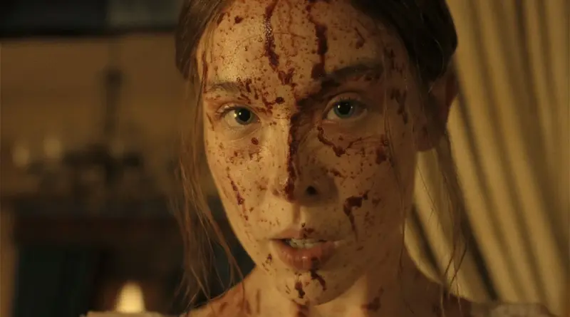 Primer plano del rostro de Lizzie totalmente salpicado de sangre en Monstruo: La historia de Lizzie Borden.