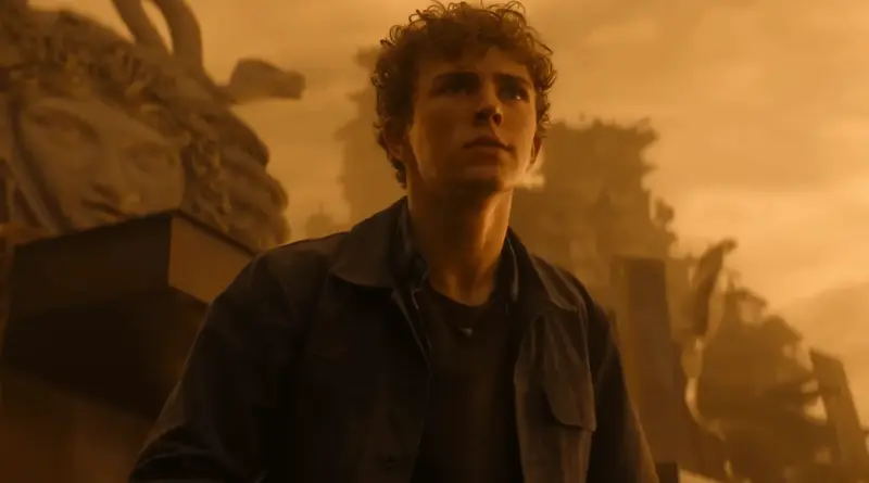 Percy Jackson iluminado por una luz dorada frente a unas ruinas en la temporada 3 de ‘Percy Jackson y los dioses del Olimpo’.