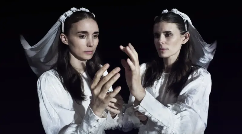 Las actrices Rooney y Kate Mara vestidas de novias sobre un fondo negro, con las manos alzadas en actitud enigmática en Bucking Fastard.
